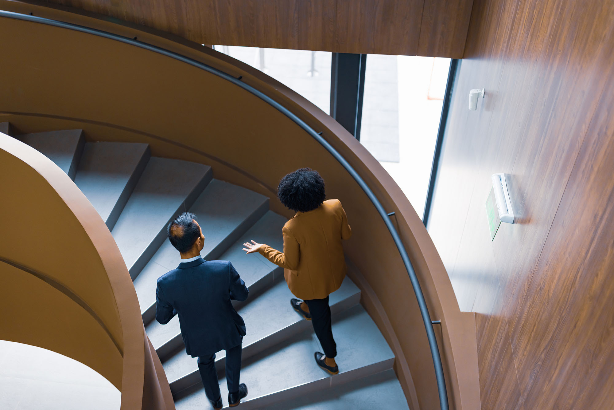 Two professionals walking down a curved indoor staircase